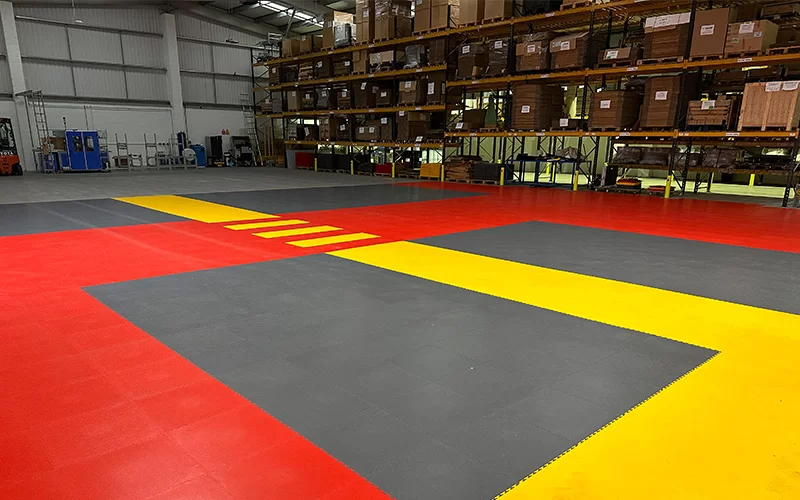 A warehouse using ecotile flooring grey, yellow and red to create walkways